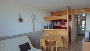 Ein gemütlicher Wohnbereich mit einer Couch, einem Holztisch und einer Küchenzeile.