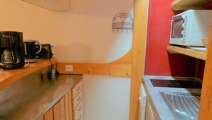 Eine kleine Küche mit Holzschränken, einer Kaffeemaschine, einer Mikrowelle und einem Spülbecken.