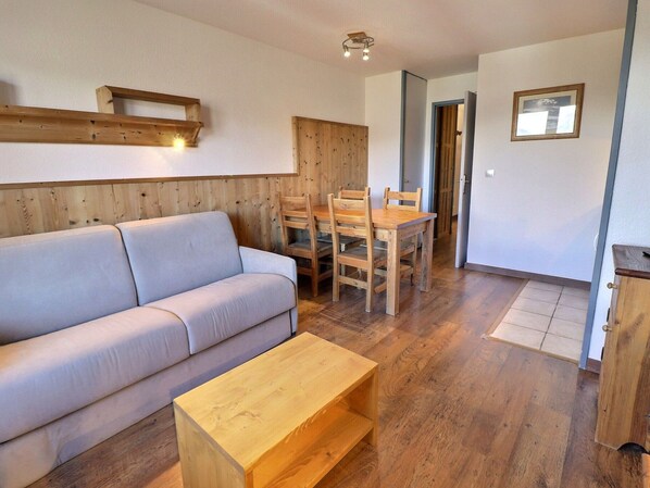 Un salon confortable avec un canapé, une table à manger en bois et des chaises.