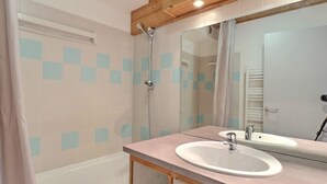A bathroom with a bathtub, a shower, a sink, and a mirror. - Comfortable 2-Room, Ski-In/Ski-Out, Close to Shops (La Tania)