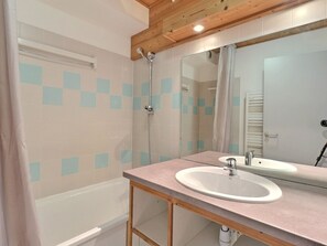 A bathroom with a bathtub, a shower, a sink, and a mirror. - Comfortable 2-Room, Ski-In/Ski-Out, Close to Shops (La Tania)