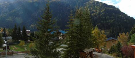 A mountain view with a small lodge, a parking area, and a few buildings in the foreground.