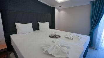 A neatly made bed with white linens, a tray with tea and sugar, and towels arranged on the bed.