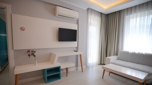 Un salon moderne doté d’un téléviseur à écran plat fixé au mur, d’un canapé blanc, d’une table basse blanche et d’un meuble de rangement de couleur turquoise.