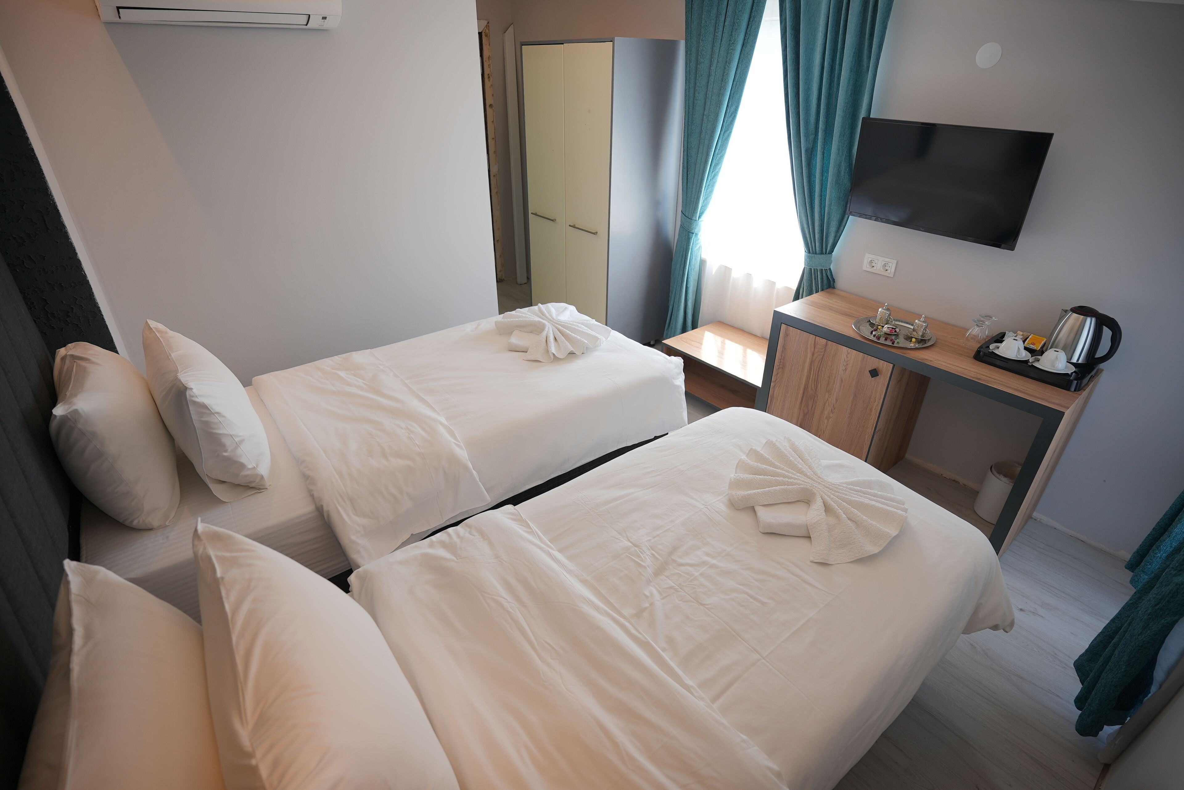 Habitación de hotel con dos camas, un escritorio, un televisor y un armario.