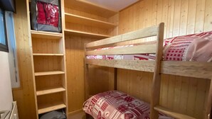 Ein Schlafraum mit Etagenbetten, Holzwänden und Regalen.