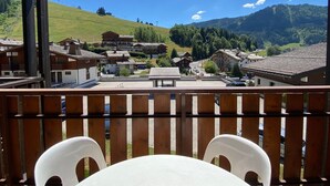 Ein Balkon mit Holzbalkon, der auf ein Dorf mit traditionellen Häusern und einem Berg im Hintergrund blickt.