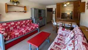 Ein Wohnzimmer mit rotem Sofa, einer roten Bank und einem Essbereich mit Holztisch und Stühlen.
