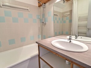 Baño con bañera, dos lavamanos, un espejo y ducha.