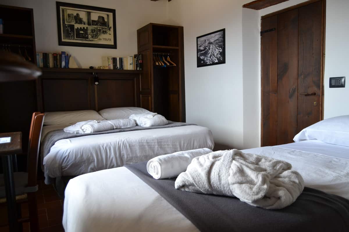 Et hotelværelse med to senge, et skab og et skrivebord.