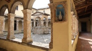An interior courtyard with arches, a statue, and a tiled floor. - Convento dei Cappuccini (Tolfa)