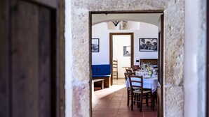 A dining area with a table set for a meal, a blue bench, and framed pictures on the wall. - Convento dei Cappuccini (Tolfa)