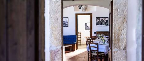 A dining area with a table set for a meal, a blue bench, and framed pictures on the wall.