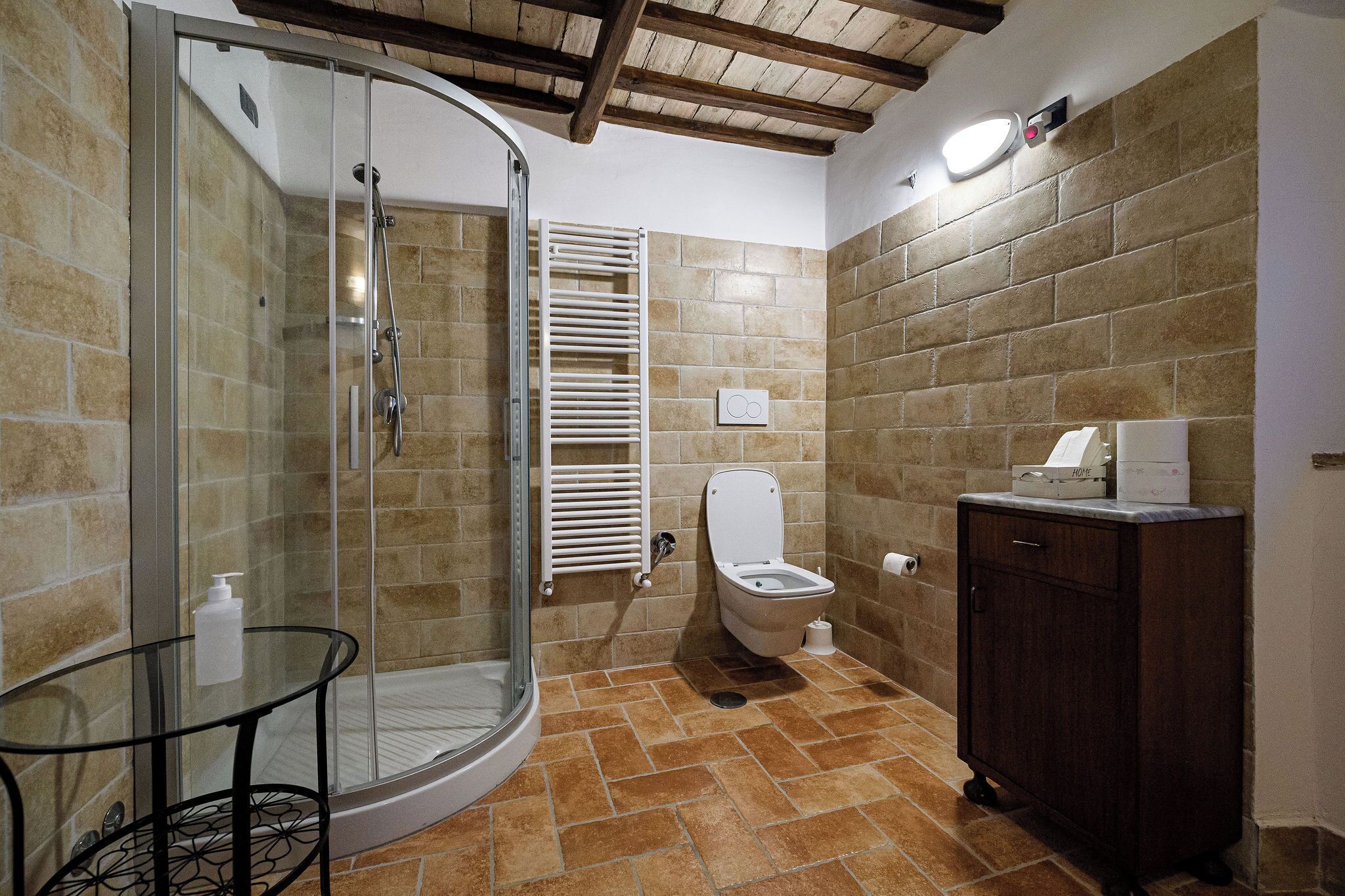 A bathroom with a glass shower enclosure, a toilet, a sink with a cabinet, and a towel rack.