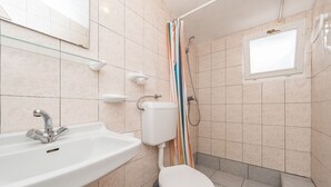 A bathroom with a sink, toilet, shower, and a window. - Apartment Bubanovic (Vir)