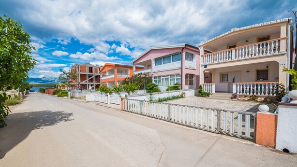 A residential street with houses, a clear sky, and a distant mountain. - Apartment Bubanovic (Vir)