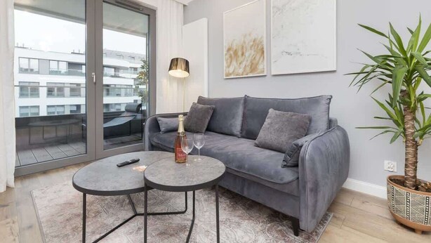 A modern living room with a grey sofa, a round coffee table, and a potted plant.