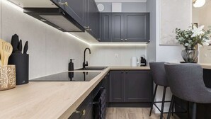 A modern kitchen with dark cabinets, a wooden countertop, and two bar stools.