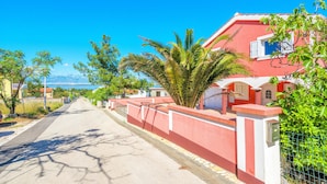 A street lined with red houses, a palm tree, and a clear blue sky. - Apartments Kopi (Vir)
