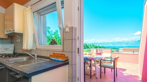 A kitchen with a view of a balcony and a dining area. - Apartments Kopi (Vir)