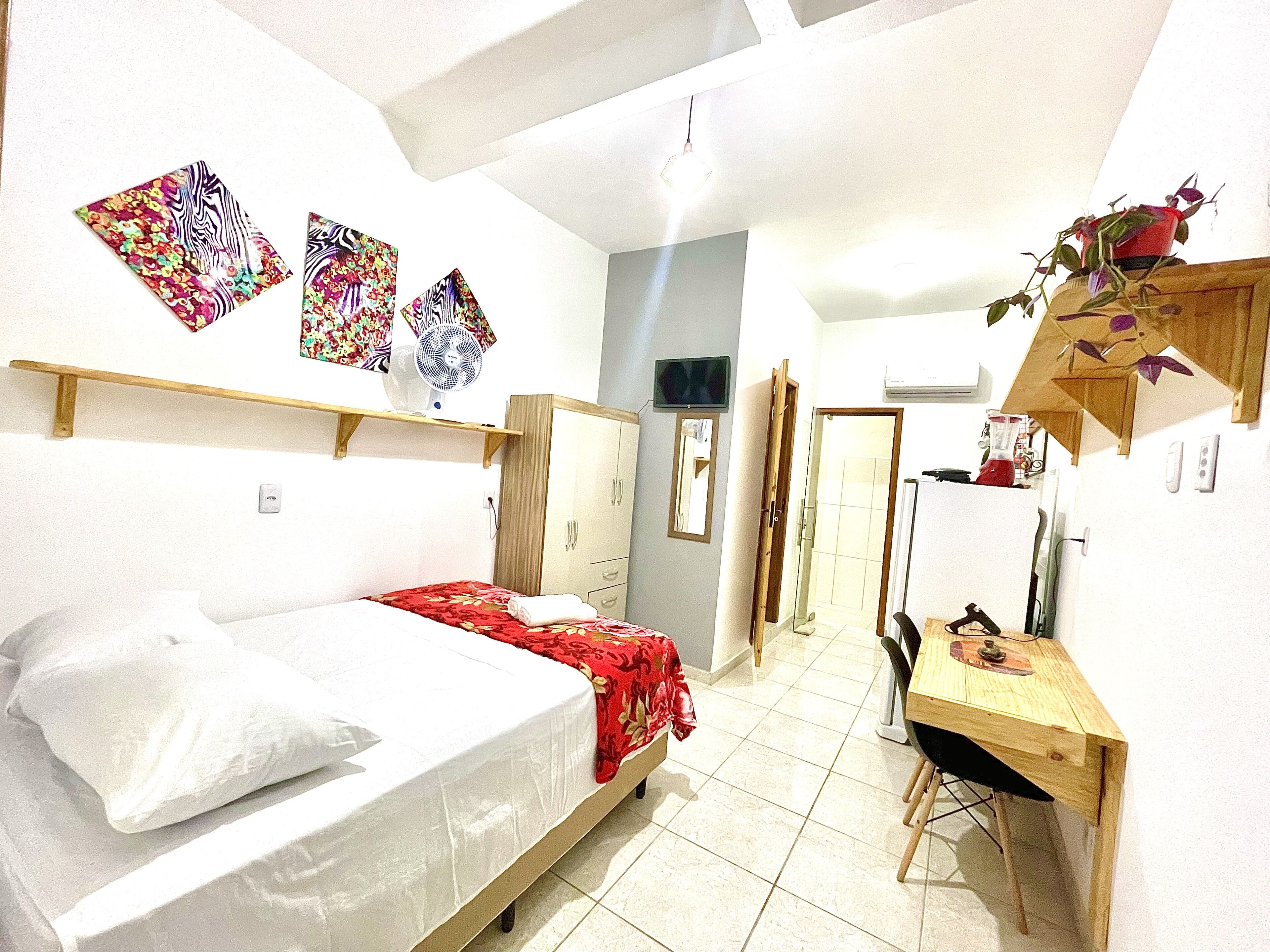 A compact bedroom with a single bed, a wooden desk, and a small table.