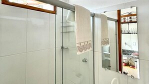 Ett badrum med en duschavdelning med glasväggar, en vit tvättställ och en spegel med en dekorativ ram.