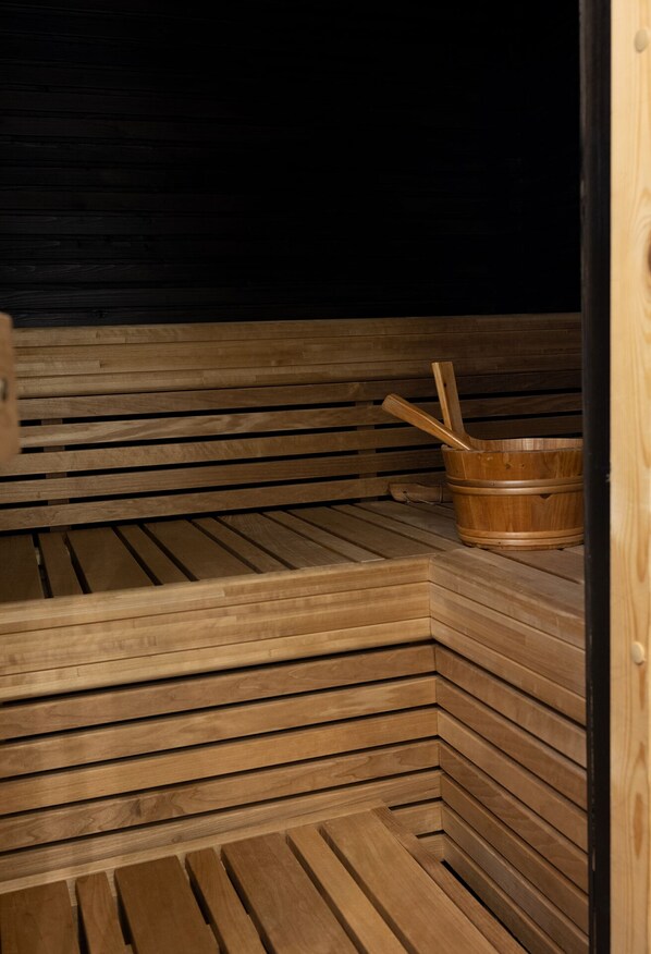 Relax in a serene sauna with a U-shaped bench and a bucket at hand.