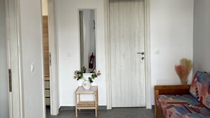 A modern bedroom with a bed, a small wooden table with a vase, and a mirror on the wall. - Antigoni Apartments (Corfu)