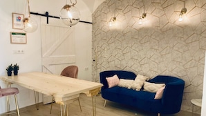 A modern dining area with a wooden table, a blue sofa, and a unique geometric wall design. - Piedra de Luna (Merida)