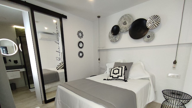 A modern bedroom with a bed, bedside tables, a mirror, and decorative wall art. - Piedra de Luna (Merida)