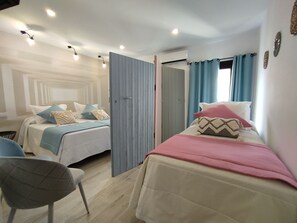 Un dormitorio con dos camas, una silla y un equipo de aire acondicionado.
