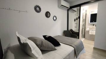 Un dormitorio con cama, almohadas, un espejo y aire acondicionado instalado en la pared.