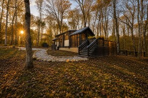 Een chalet met een houten gevel, een pad van stenen dat er naartoe leidt, en een bebost achtergrond.