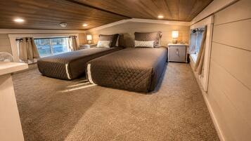 A bedroom with two beds, a nightstand, a bedside table, and a window with curtains.