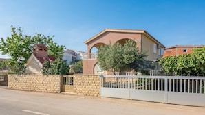 Un barrio residencial con una casa de ladrillo, un balcón y un muro de piedra.