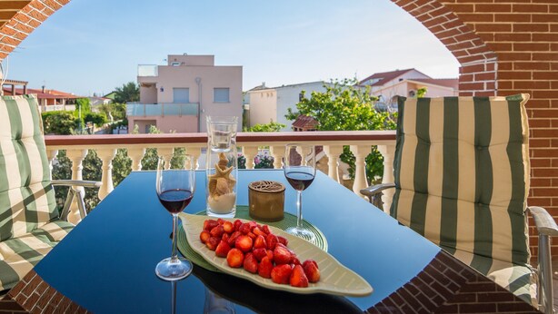 Una mesa de comedor con un plato de fresas, dos copas de vino y un objeto decorativo.