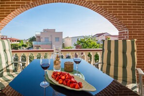 A dining table with a plate of strawberries, two wine glasses, and a decorative item. - Apartments Filipovic (Vir)