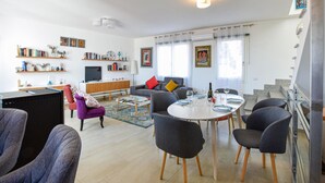 A modern living room with a sofa, chairs, a dining table, and a TV. - Beautiful apartment in Sant'Antioco (Sant'Antioco)