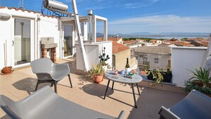 A rooftop terrace with a table set for two, a grill, and potted plants. - Beautiful apartment in Sant'Antioco (Sant'Antioco)
