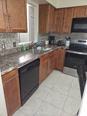 A kitchen with wooden cabinets, a dishwasher, a stove, a microwave, and a coffee maker.