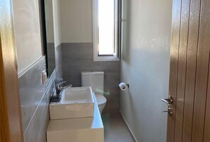 A compact bathroom with a toilet, sink, and window.