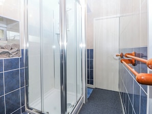 Una ducha con puerta de vidrio, un perchero y una pared con azulejos azules.