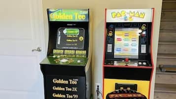 Two arcade machines, 'Golden Tee' and 'Pac-Man', with a stool in front of the 'Pac-Man' machine.