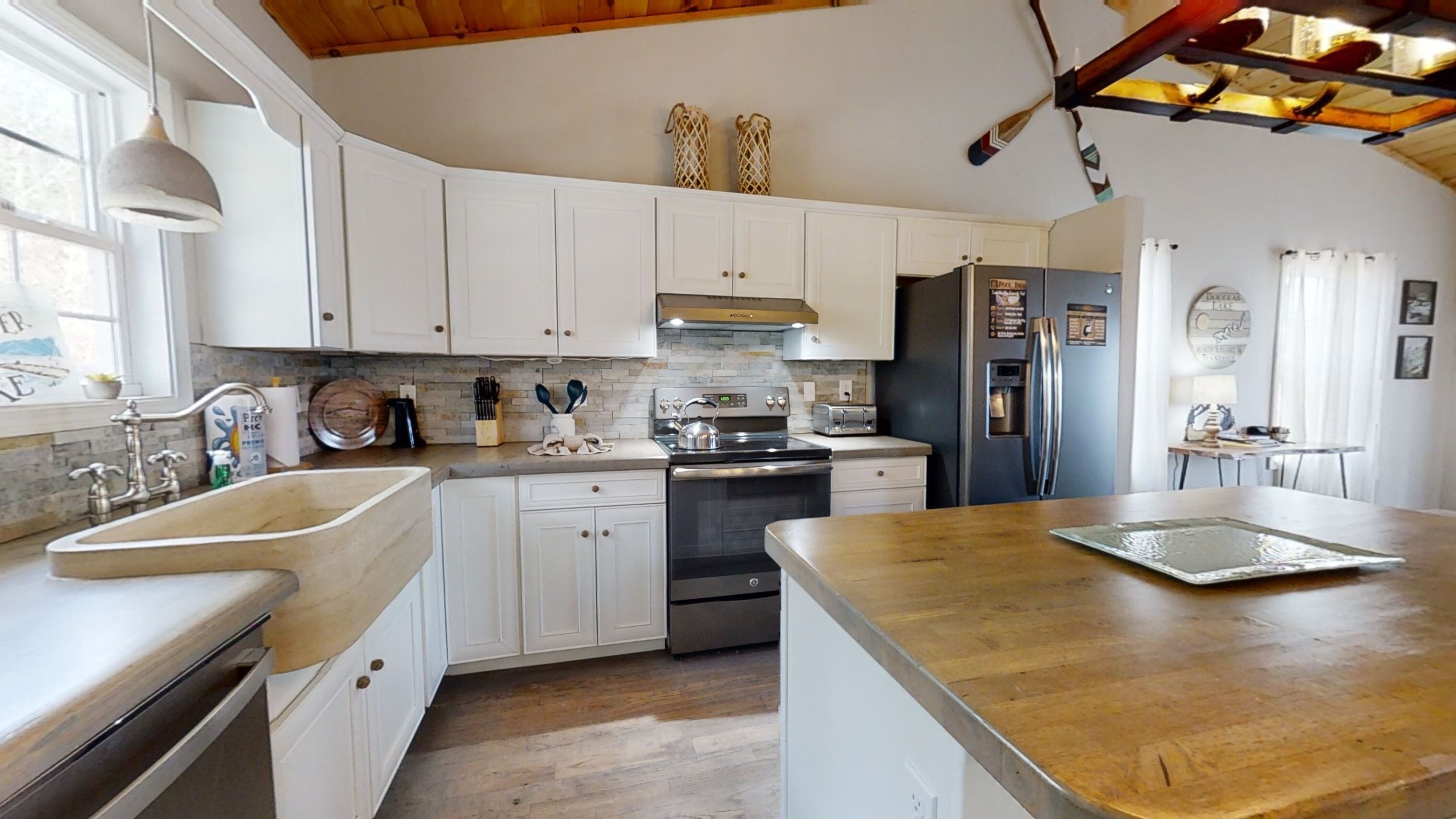 Una cocina con armarios blancos, un refrigerador de acero inoxidable, una estufa y una encimera de madera.