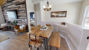 A dining area with a wooden table and benches, a chandelier, and a mirror on the wall.