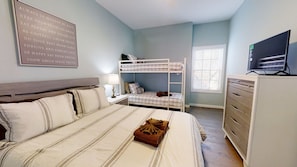 A bedroom with a bunk bed, a bedside table with a lamp, a dresser, and a TV. - Above The Cove 3 Bedroom Home by RedAwning (Sevierville)