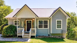 A two-story house with a front porch, a mailbox, and a 'Welcome' sign.