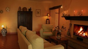 A cozy living room with a fireplace, a sofa, a chair, and a table with a vase.