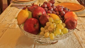 A dining table set with plates, cutlery, and a fruit bowl.