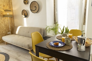 Relax in this serene living space, featuring a sofa, dining table, and potted plant.